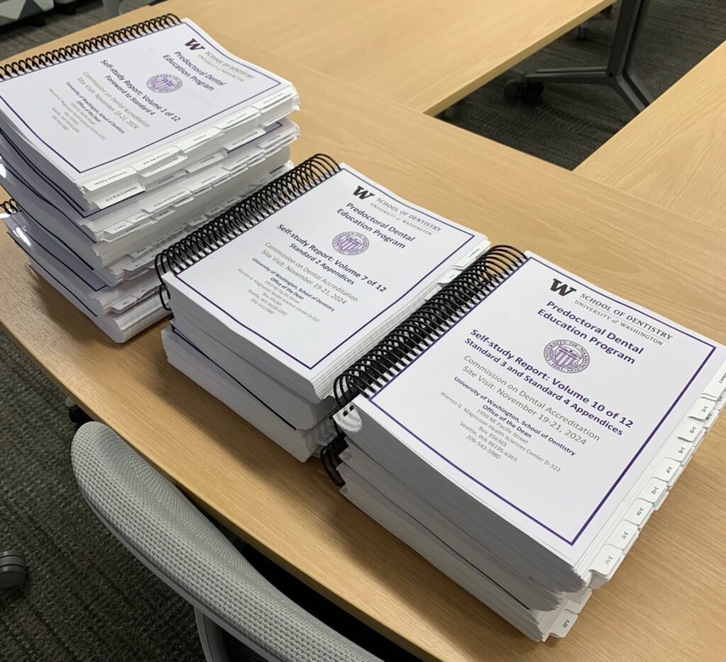 12 large spiral-bound reports in 3 stacks.