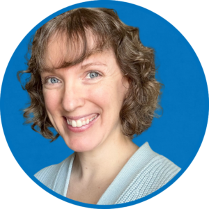 Woman with pale skin and curly brown hair wearing a light blue cardigan.